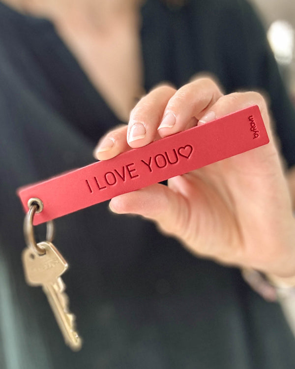 SOLO Large nøkkelring i rødt skinn holdt frem i hånden med nøkkel og graveringen "I love you" ♡