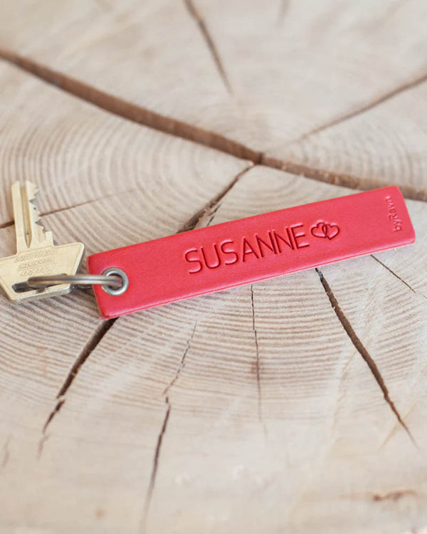 SOLO Medium nøkkelring i rødt skinn med navnet "Susanne" og to hjerter gravert, med nøkkel på treskive
