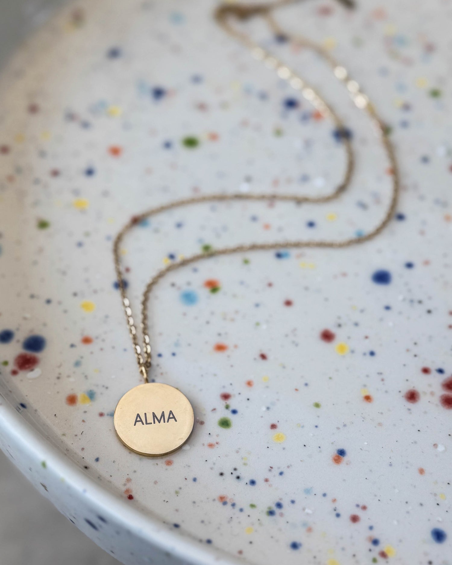 Navnehalskæder og navnegaver hos byRavn – her keyhanger i cognac læder med navnene "Karl ♡ Anna" præget, holdt i hånden