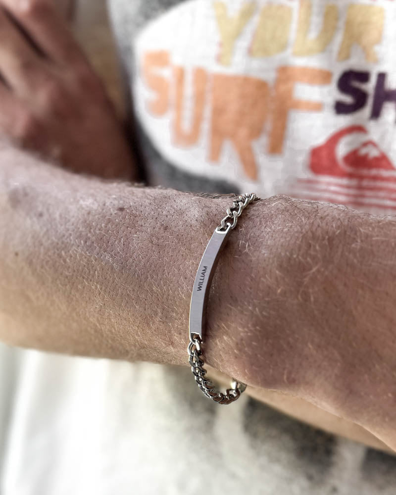 ARA navnearmbånd i sølvfarget rustfritt stål med navnet "William" gravert, båret rundt håndleddet på stranden