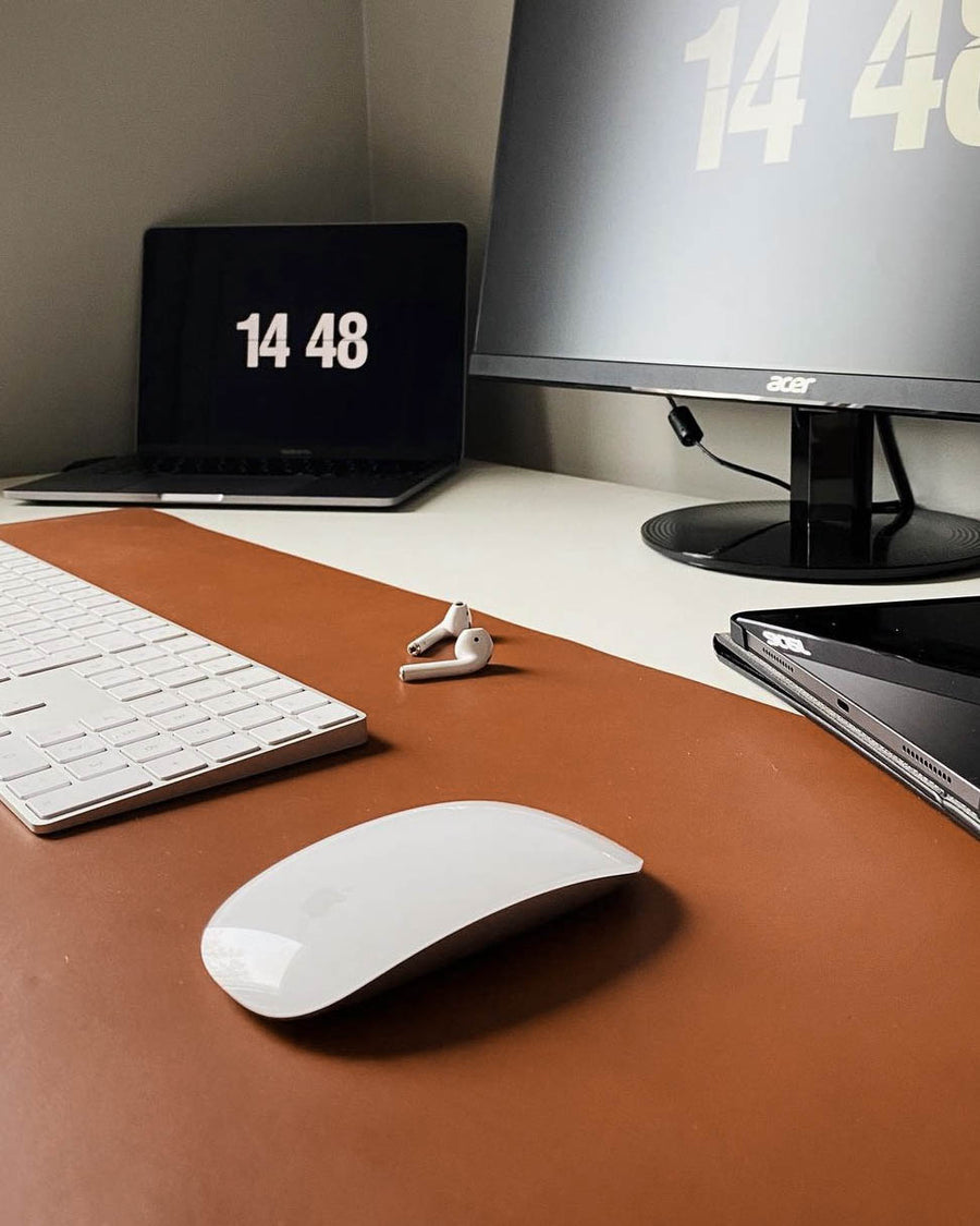 DESK skriveunderlag i cognac skinn på skrivebord med tastatur, mus, ørepropper, laptop og skjerm