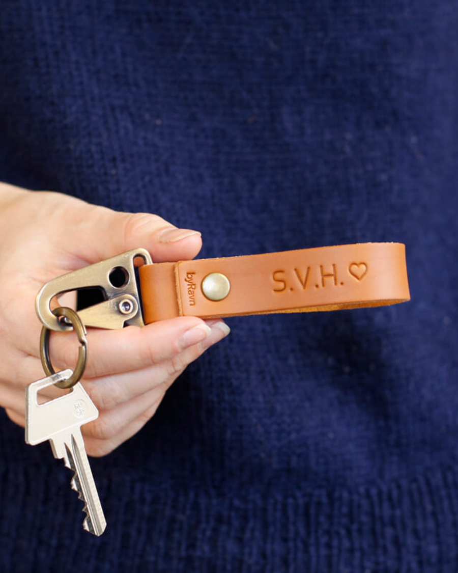 HOOK nøkkelring i cognac skinn holdt i hånden med nøkkel og initialene "S.V.H." ♡ gravert