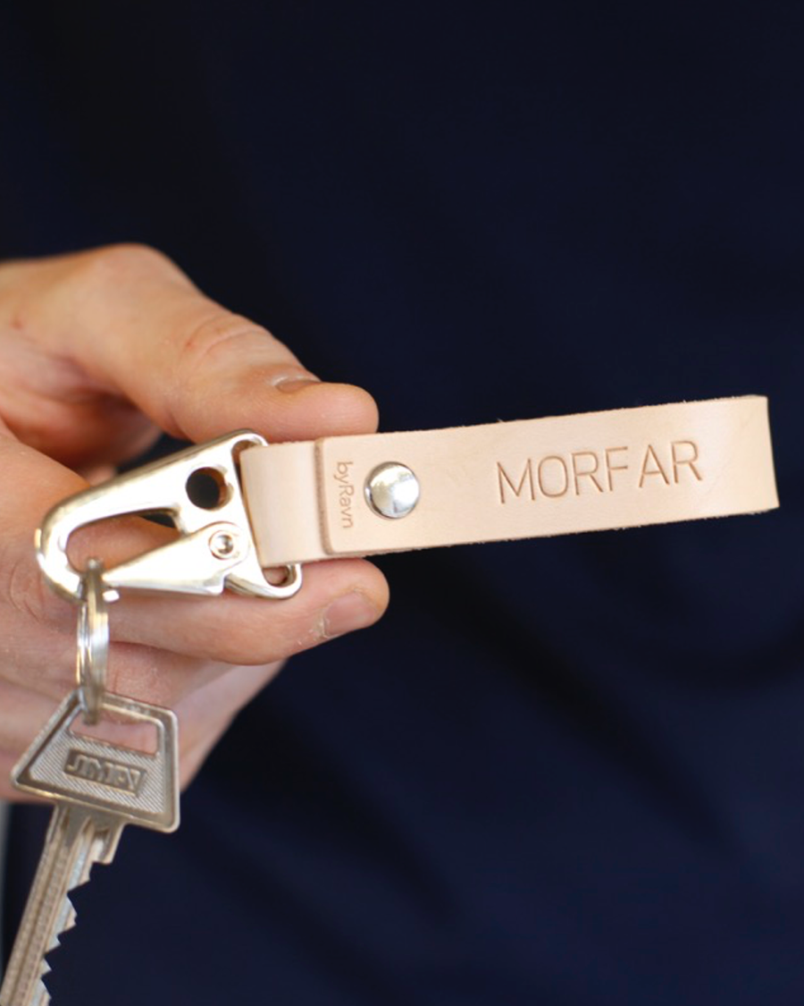 HOOK nøkkelring i naturfarget skinn med karabinkrok i stål og graveringen "Morfar", holdt i hånden med nøkkel