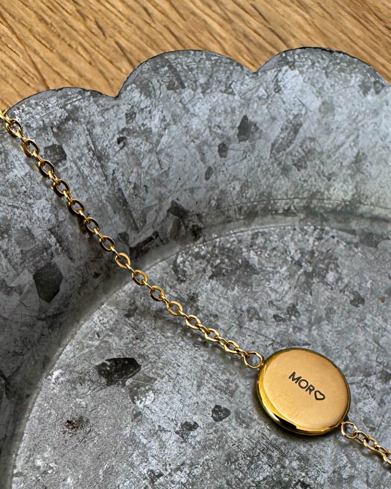 IBI QUOTE armbånd i gullbelagt stål med graveringen "Mor" ♡ på rund plate, liggende på sinkfat