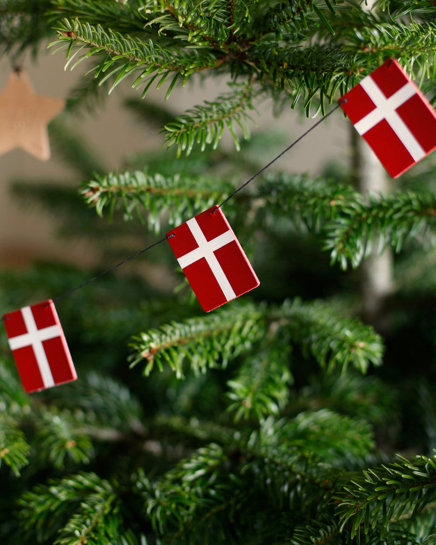SALUT flaggrekke med Dannebrog-flagg i skinn hengt som julepynt i grønt juletre med trestjerne