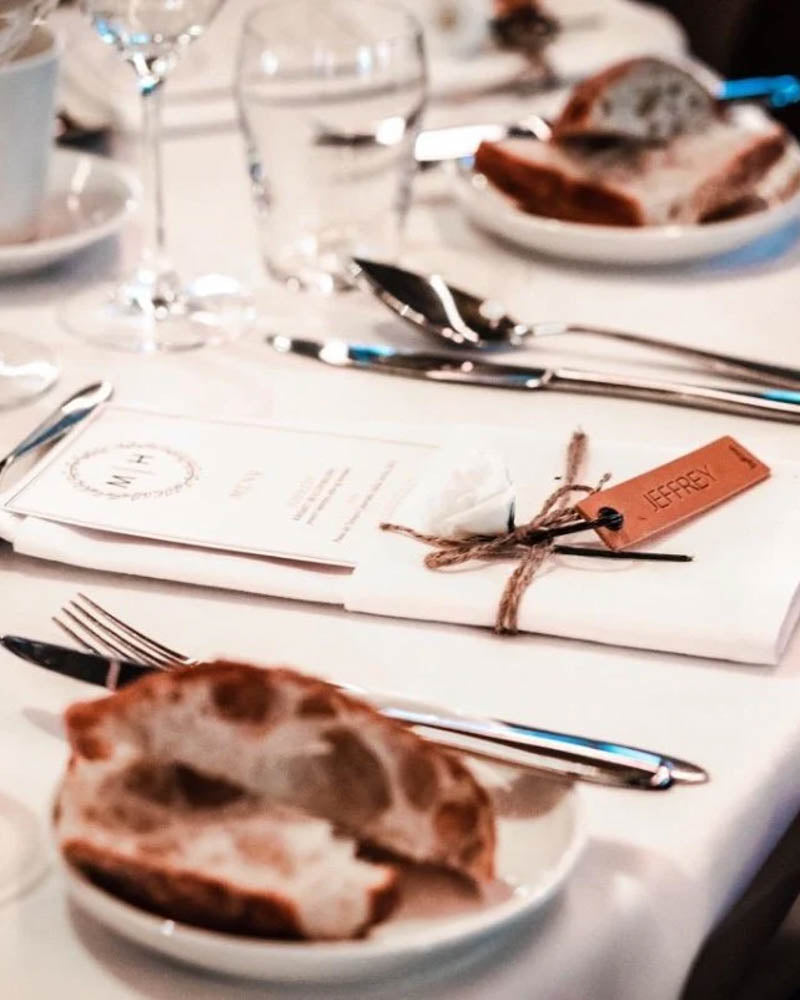 Prøve på MERRY bordkort i cognac skinn med navnet "Jeffrey" gravert ved menykort og brød på festbordet
