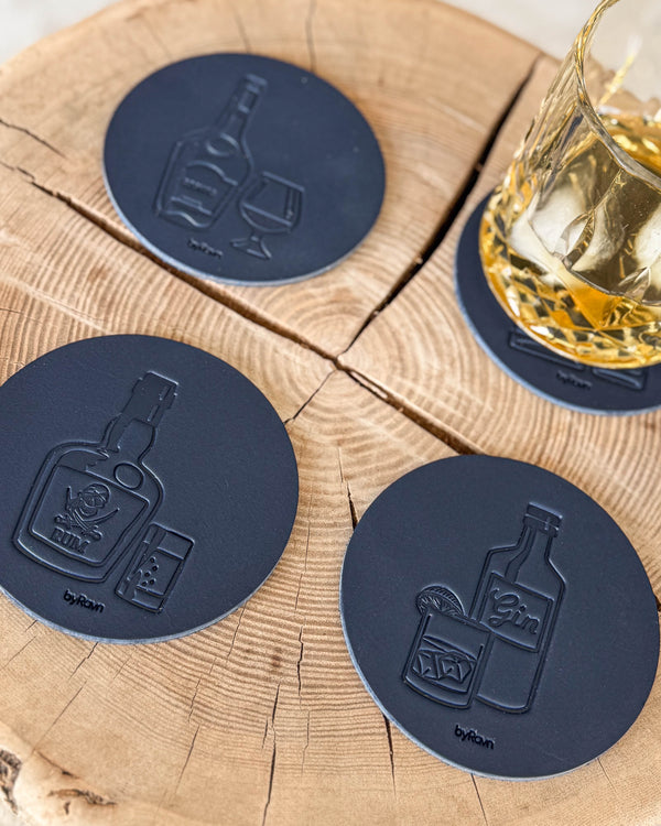 MOKKA glassbrikker i mørkeblått skinn med brennevinsmotiver cognac, rom og gin på treskive ved krystallglass med whisky og is