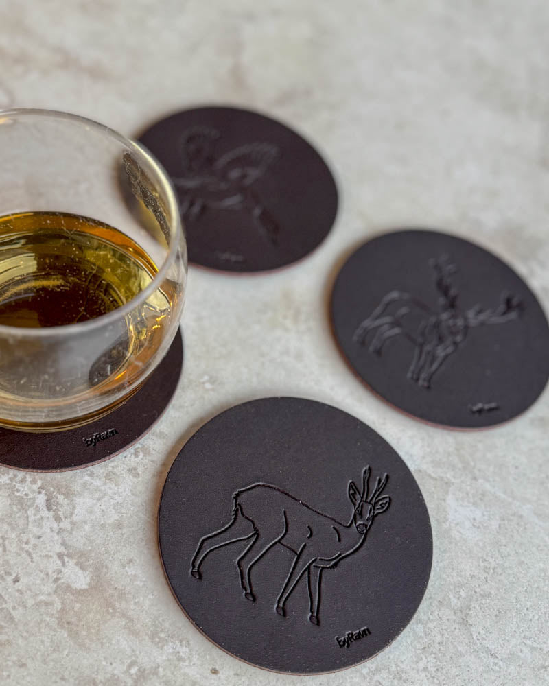 MOKKA jakt-glassbrikker i mørkebrunt skinn preget med råbukk, stokkand og kronhjort på lyst bord ved glass whisky