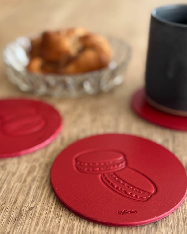 MOKKA kaffe & kake-glassbrikke i rødt skinn preget med macarons på trebord ved svart kopp og kanelsnurr i glasskål