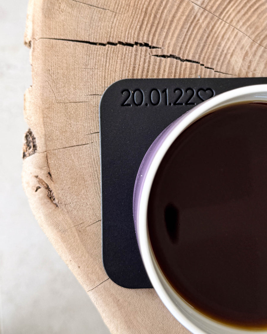MOKKA firkantet glassbrikke i svart skinn med personlig gravering "20.01.22" ♡ under kaffekopp på treskive