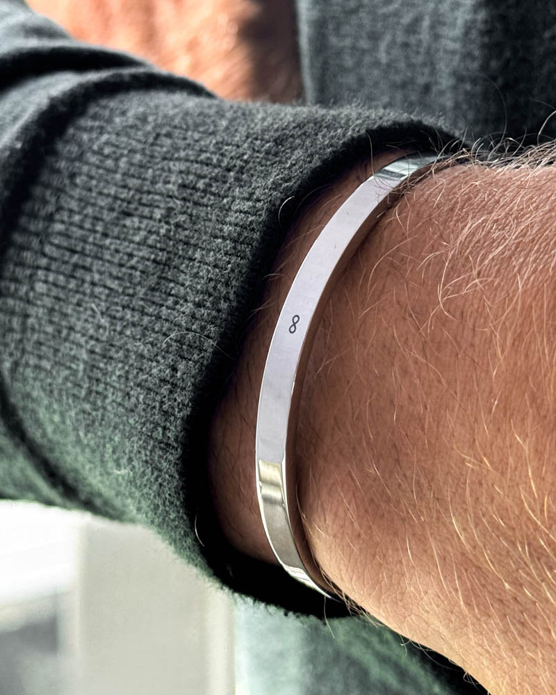 MARS armbånd i sølvfarget rustfritt stål med uendelighetstegn ∞ gravert rundt håndleddet, mørkegrønn strikk