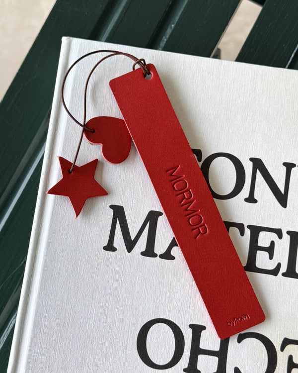 PAGE bokmerke i rødt skinn med graveringen "Mormor" og rødt hjerte og stjerne på snor, liggende på hvit bok