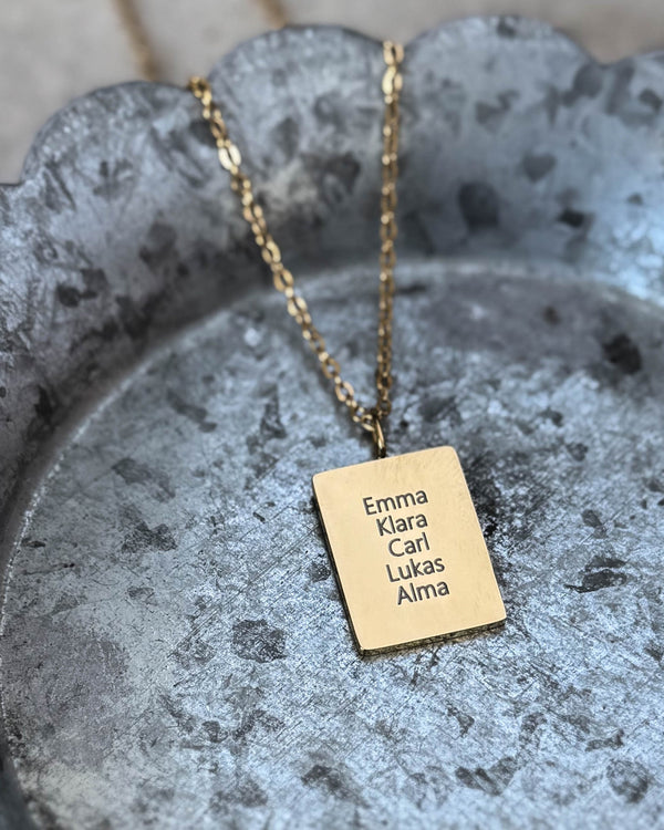 RAZ navnehalskjede i gullbelagt stål med navnene "Emma Klara Carl Lukas Alma" gravert på rektangulær plate, på bølgekantet sinkfat