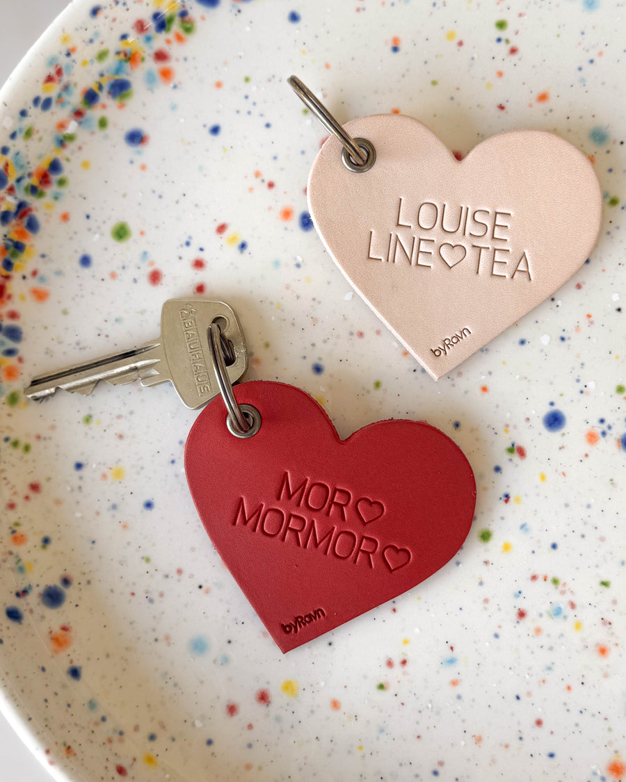 ROSE hjertenøkkelringer i naturfarget og rødt skinn med graveringene "Louise Line ♡ Tea" og "Mor ♡ Mormor ♡" på prikkete tallerken