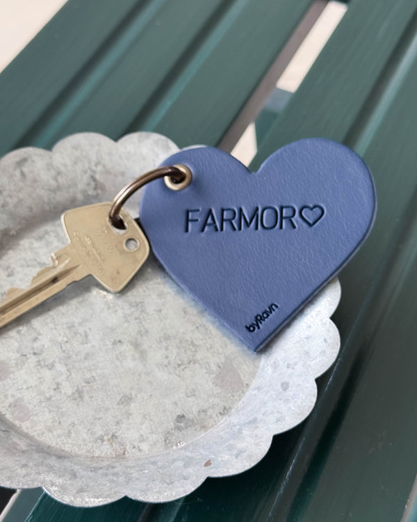 ROSE hjertenøkkelring i mørkeblått skinn med graveringen "Farmor" ♡ og nøkkel i sinkskål på grønn trebenk
