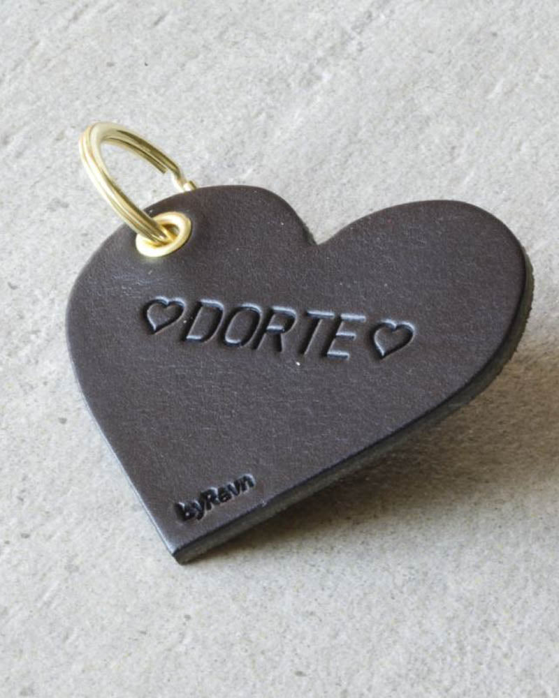ROSE hjertenøkkelring i svart skinn med personlig gravering ♡ "Dorte" ♡ og gyllen nøkkelring på lys betongbakgrunn