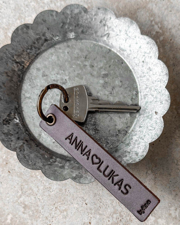 SOLO Medium nøkkelring i mørkebrunt skinn med personlig gravering "Anna ♡ Lukas" og nøkkel i sinkskål