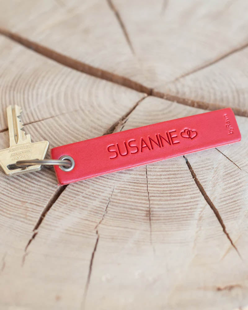 SOLO Medium nøkkelring i rødt skinn med navnet "Susanne" og to hjerter gravert, med nøkkel på treskive