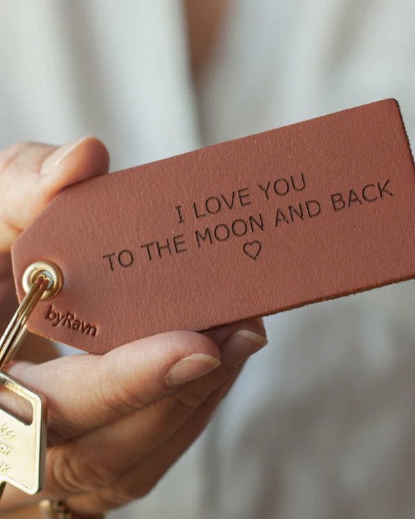 STORM nøkkelring i cognac skinn holdt i hånden med nøkkel og graveringen "I love you to the moon and back" ♡