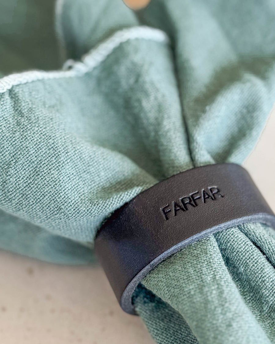 KNOT serviettring i svart skinn med graveringen "Farfar" rundt lysegrønn tøyserviett