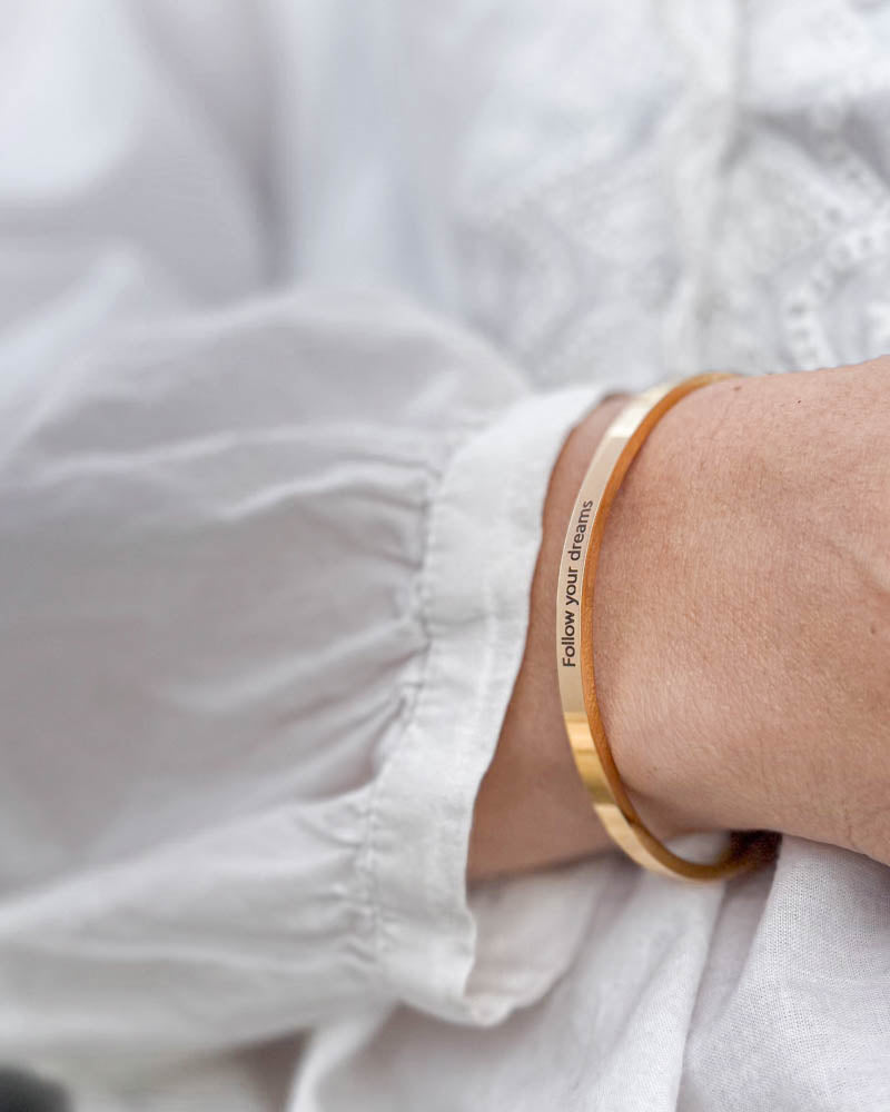 VENUS armbånd i gullbelagt stål med graveringen "Follow your dreams" til hvit bluse med puffermer