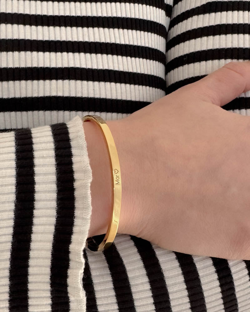 VENUS armbånd i gullbelagt stål med graveringen "Mor" ♡ rundt håndleddet, svart-hvit stripet strikk