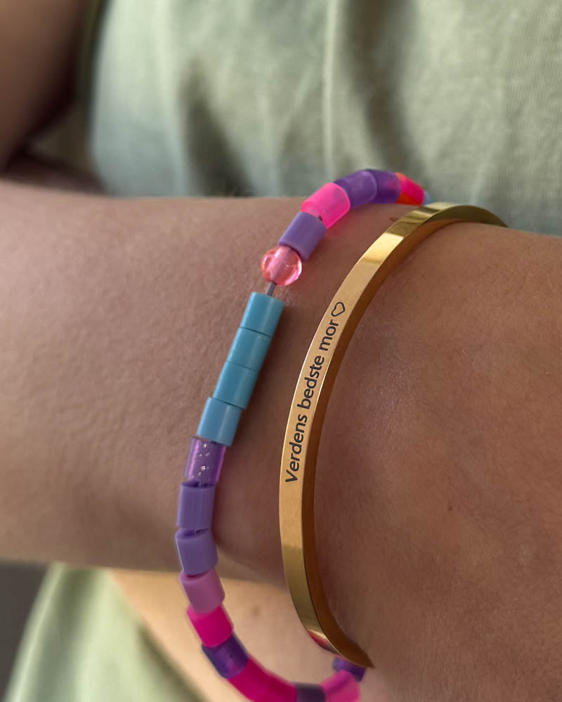 VENUS armbånd i gullbelagt stål med graveringen "Verdens bedste mor" ♡ båret sammen med fargerikt perlearmbånd